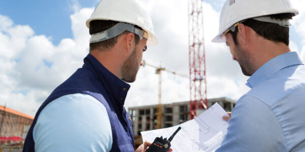 View of a Engineer and worker watching blueprint on construction site